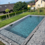 Piscine à débordement contemporaine avec margelles en pierre grise et eau turquoise, réalisée par Dodin Piscine.